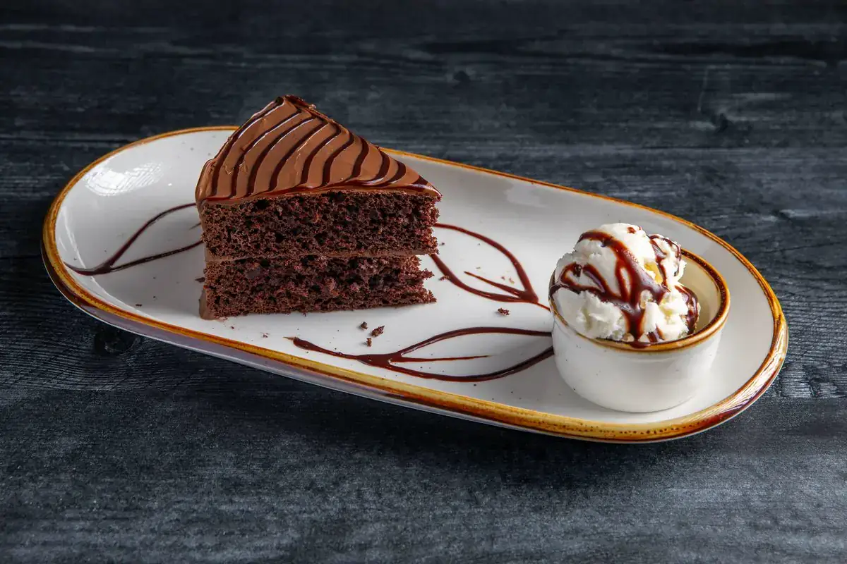 A slice of chocolate fudge cake on a white plate