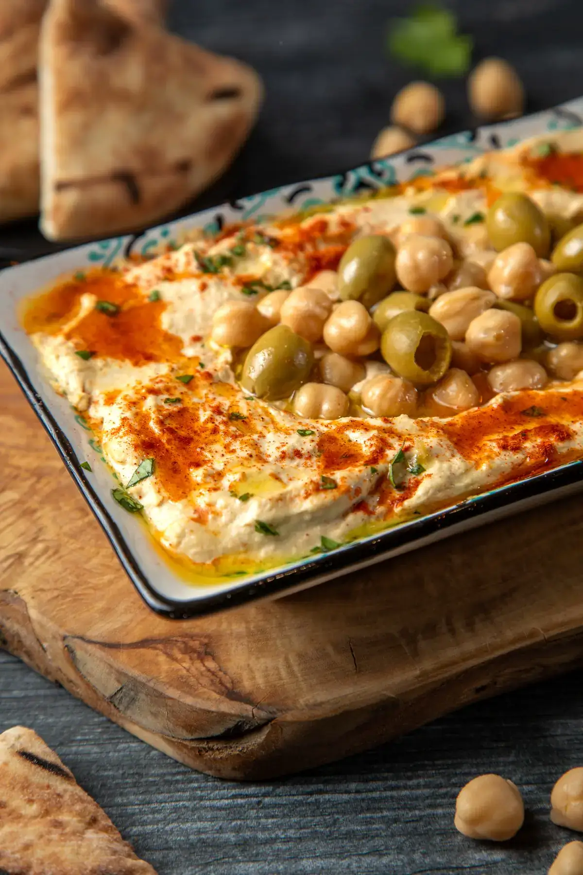 A tray of hummus topped with olives and paprika
