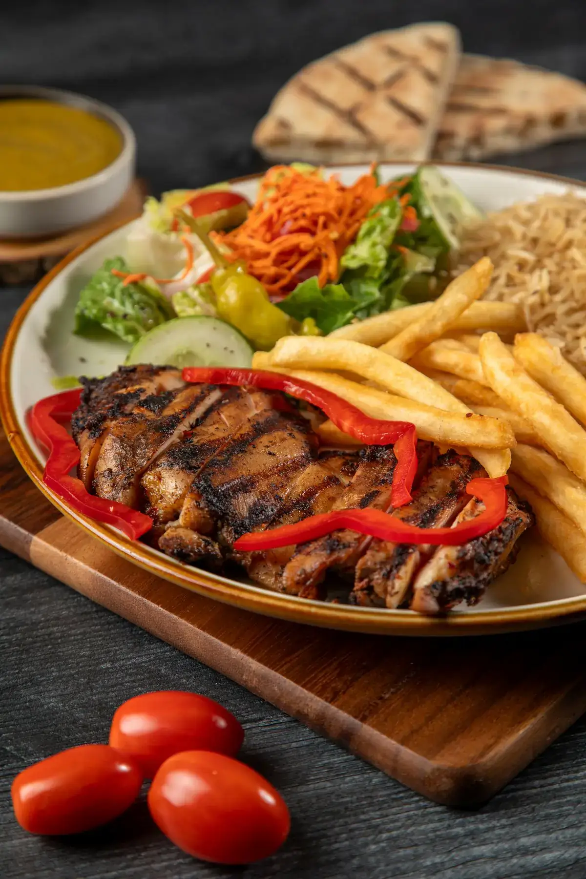 Jerk chicken with rice and salad on a dark wooden board