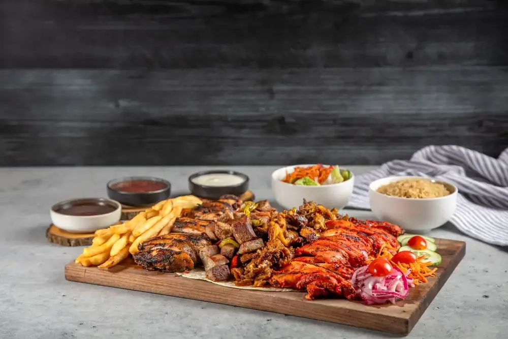 Mixed grill with rice and sides on a wooden board