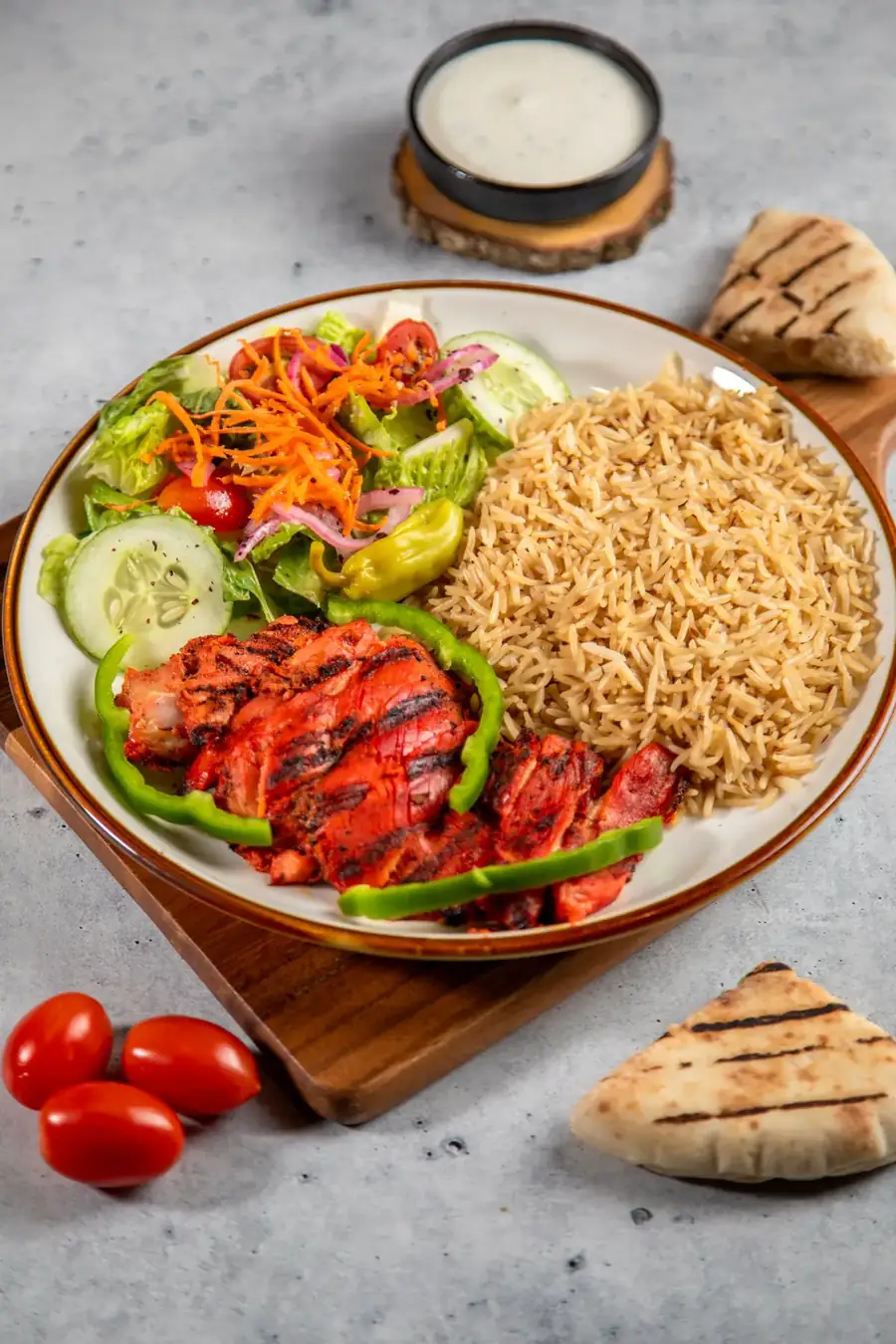 Chicken tikka with seasoned rice and salad on a round plate