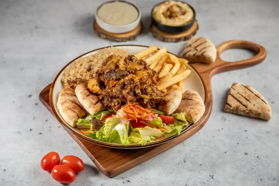 A shawarma platter on a round wooden board