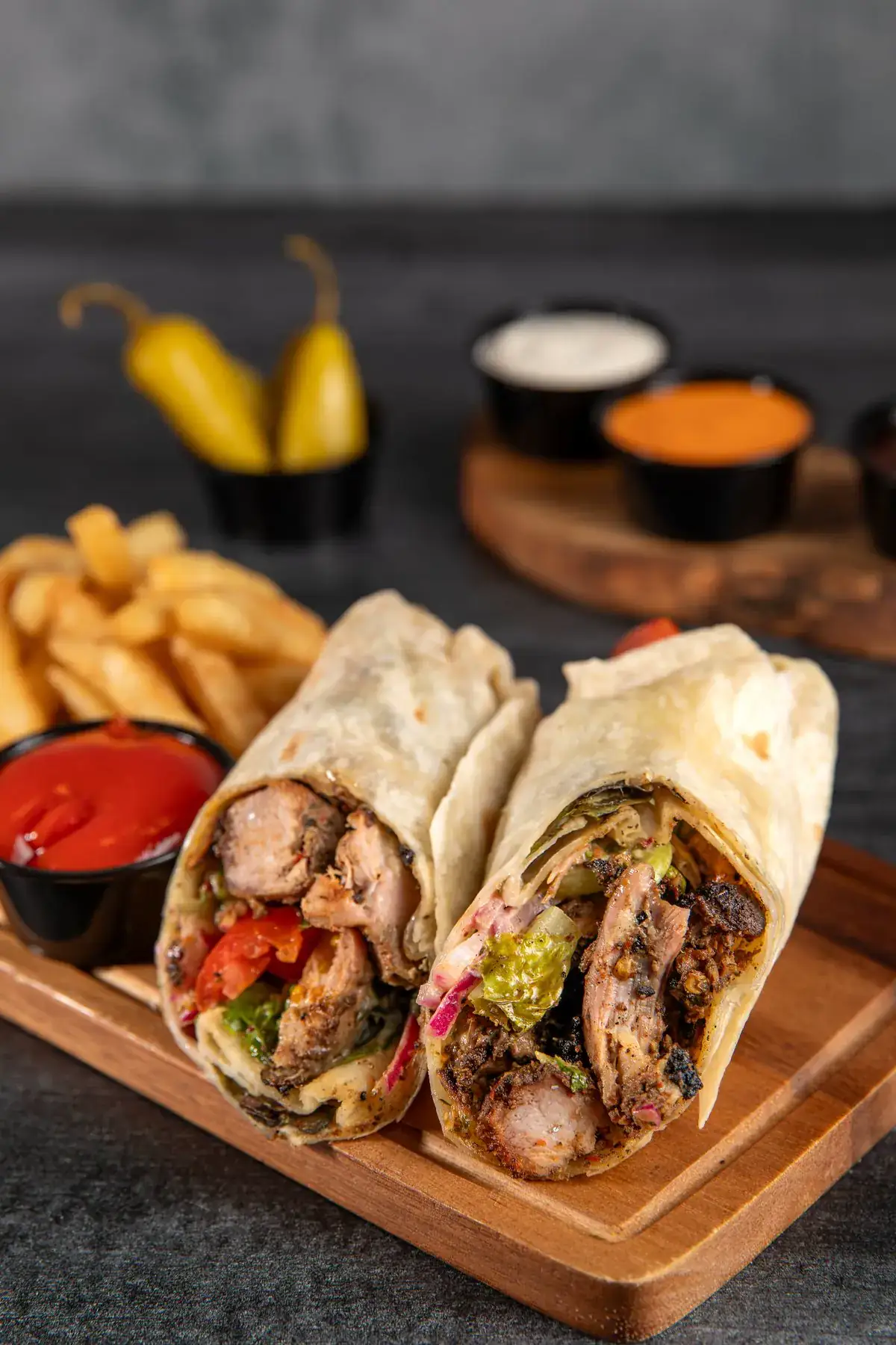 Lamb wraps cut open on a wooden board with fries